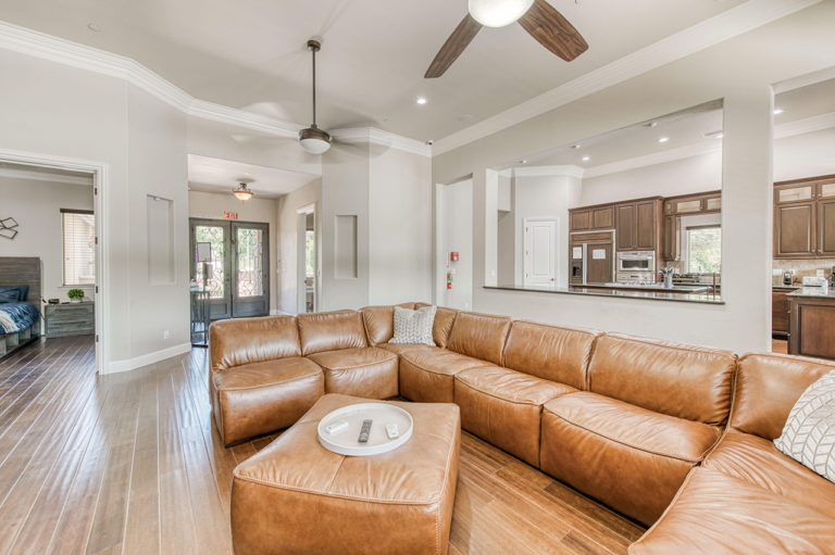 Warm and spacious living room with leather sectional and fireplace at My Time Recovery in Fresno.