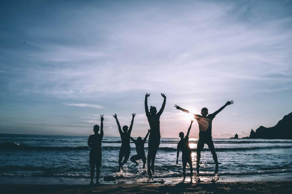 Group of people celebrating together at the beach during early recovery journey.