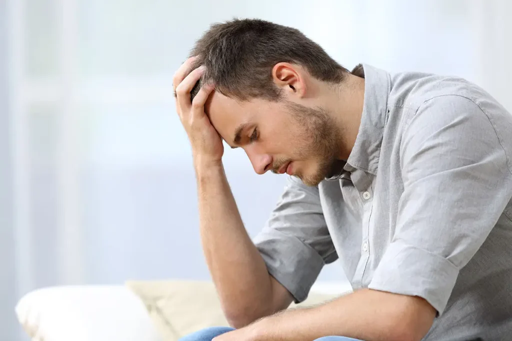 Man in distress with his hand on his forehead struggling with gabapentin withdrawal.