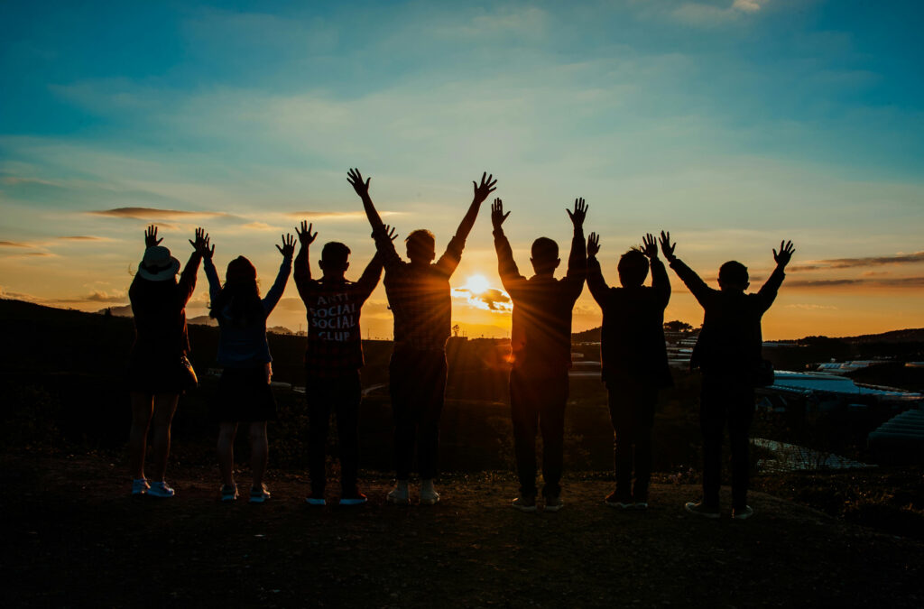 Group on a mountaintop with their hands in the air celebrating successful dual diagnosis treatment in Fresno.